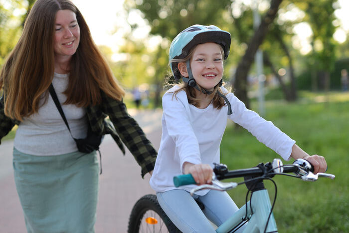 Frau hilft Mädchen beim Radfahren.