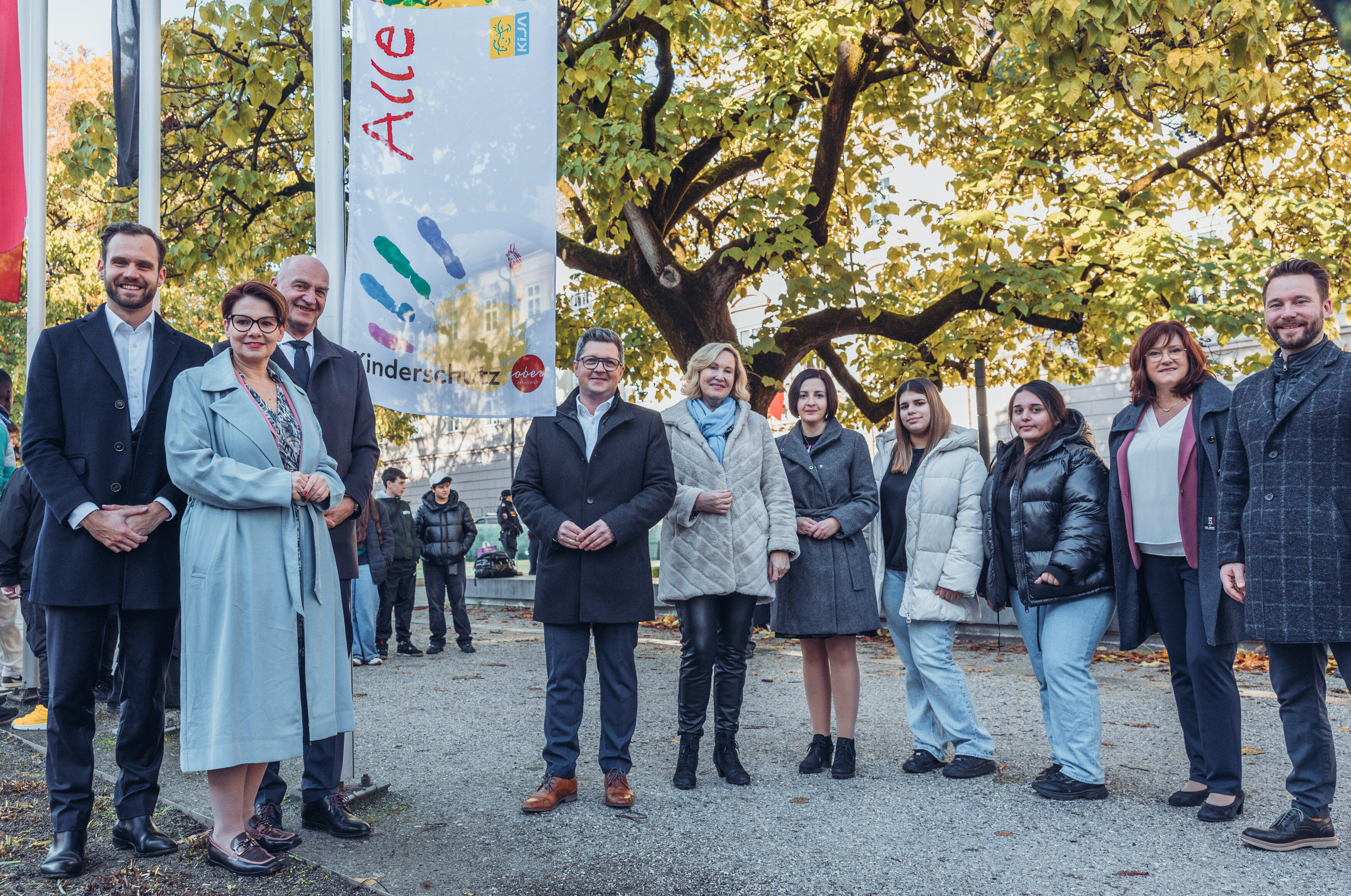 Hissen der Kinderrechte-Fahne mit Klubobmann LAbg. Mag. Felix Eypeltauer (NEOS), LAbg. Mag.a Dagmar Engl (Grüne), Klubobmann LAbg. Dr. Christian Dörfel (ÖVP), Kinderschutz-Landesrat Mag. Michael Lindner, Kinder- und Jugendanwältin Mag.a Christine Winkler-Kirchberger, LAbg. Stefanie Hofmann (FPÖ), zwei Schülerinnen der PTS Linz-Stadt 1, Klubobfrau LAbg. Sabine Engleitner-Neu, MA (SPÖ), Klubobmann LAbg. Manuel Krautgartner (MFG)