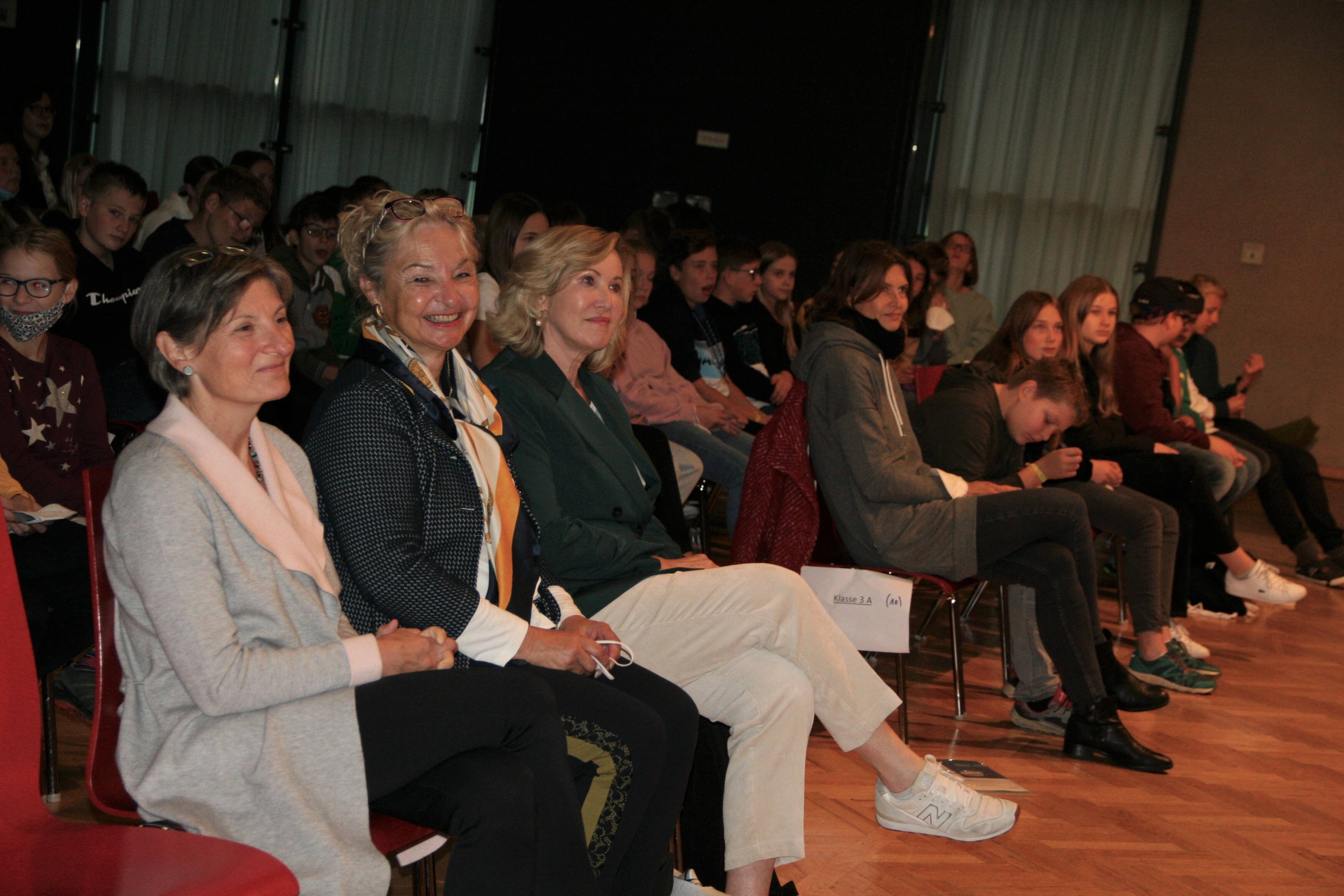 Personen sitzen im Publikum, darunter Mag.a Christine Winkler-Kirchberger