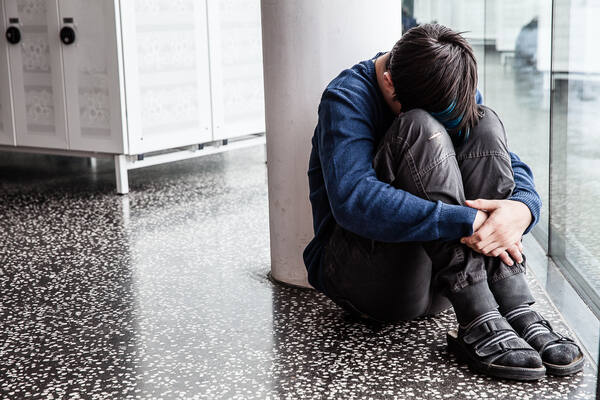 Junge sitzt verzweifelt am Boden