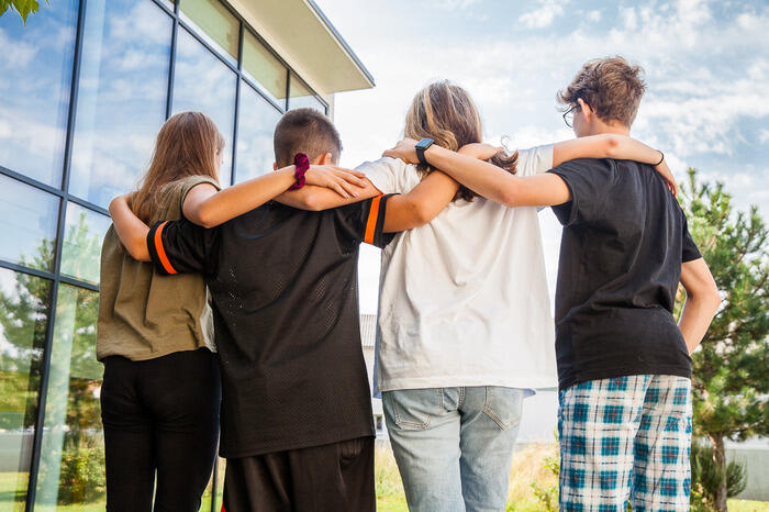 Eine Gruppe von Kindern steht mit dem Rücken zur Kamera und umarmt sich.