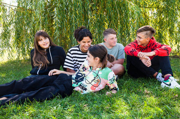 Eine Gruppe von Kindern sitzt draußen in der Wiese.